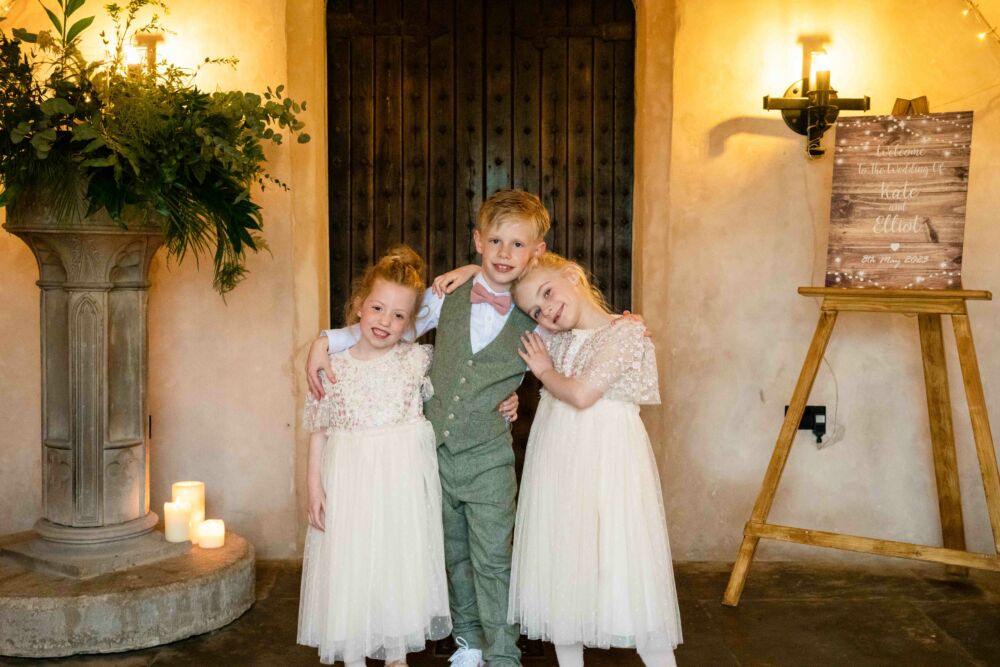 Child bridesmaids and page boy hugging 