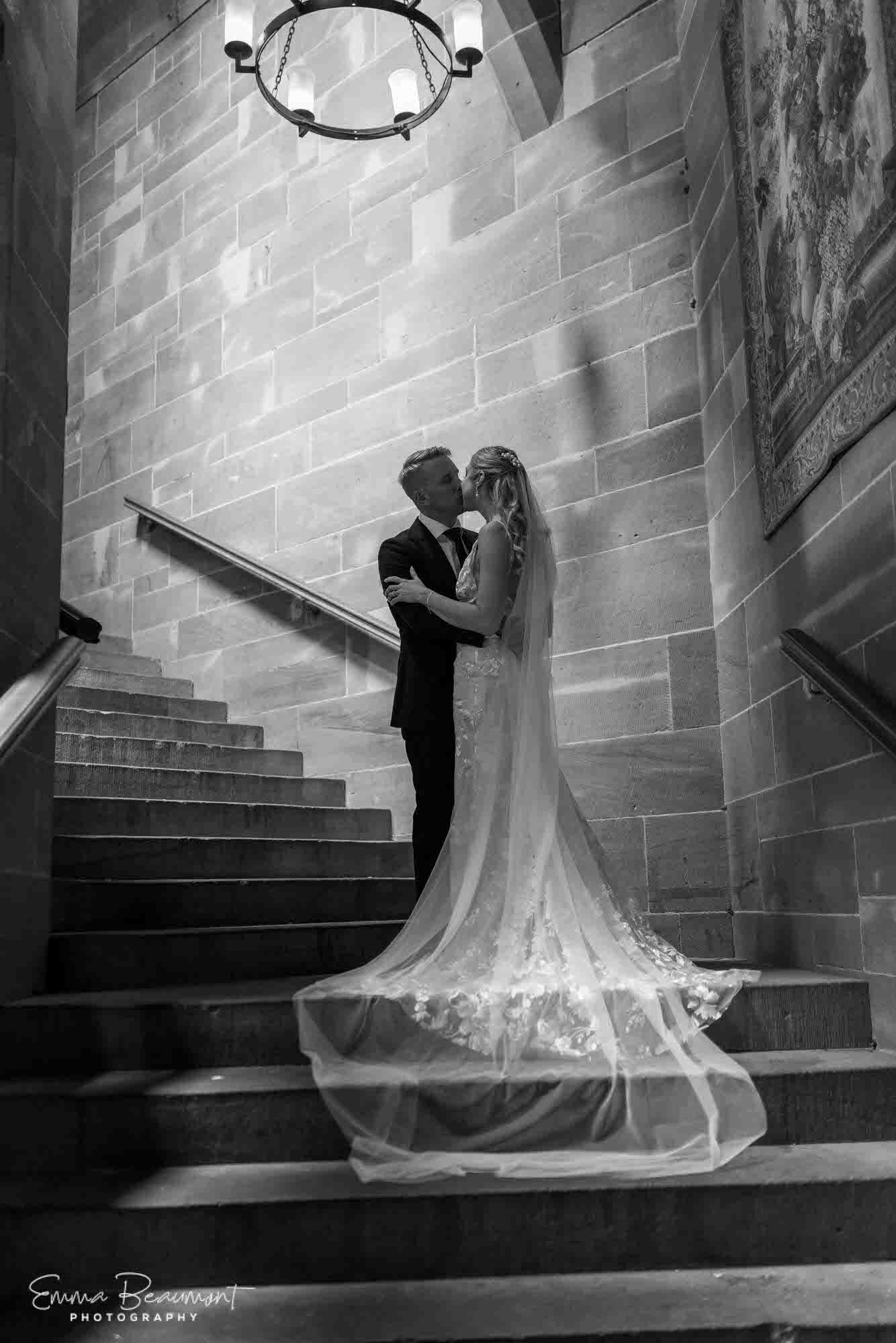 couple kiss on staircase at Peckforton Castle