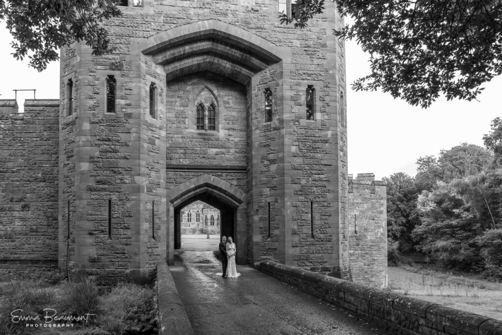 new-le-weds stand at the entrance to Peckforton Castle