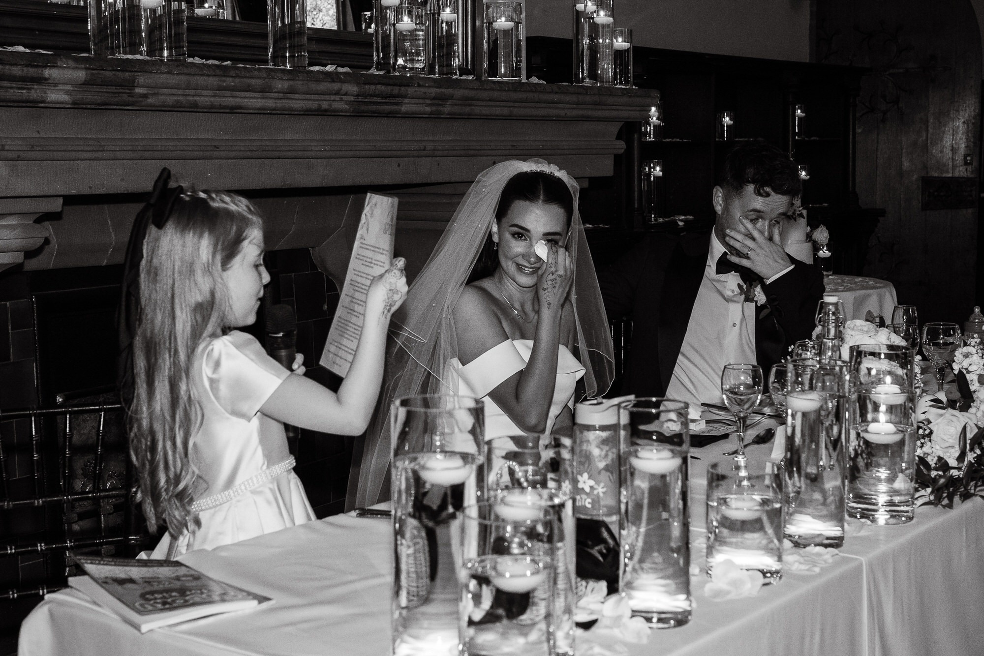 couple wipe tears as their daughter reads a speech at their wedding breakfast at Peckforton Castle in Cheshire