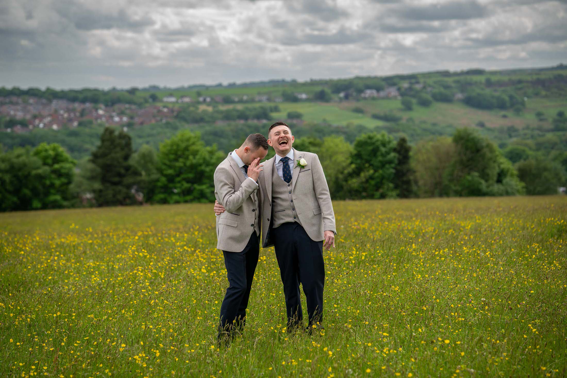 2 grooms laugh together during their wedding couples photos in the Lancashire countryside